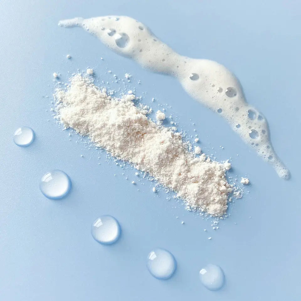 Close-up showing water droplets, ModernKind Shampoo Powder, and foamy water-activated shampoo powder lather